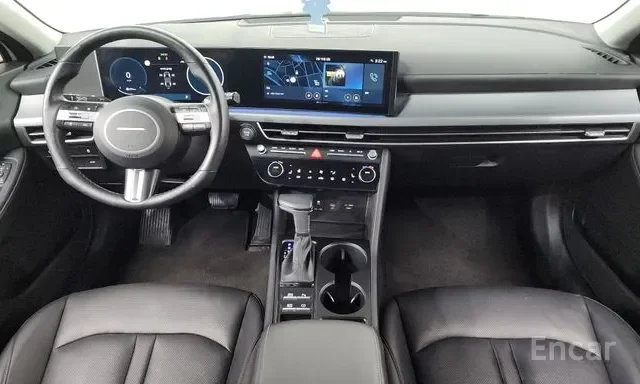 Interior of a modern car dashboard with digital display, steering wheel, gear shift, and center console with control buttons and cup holders.