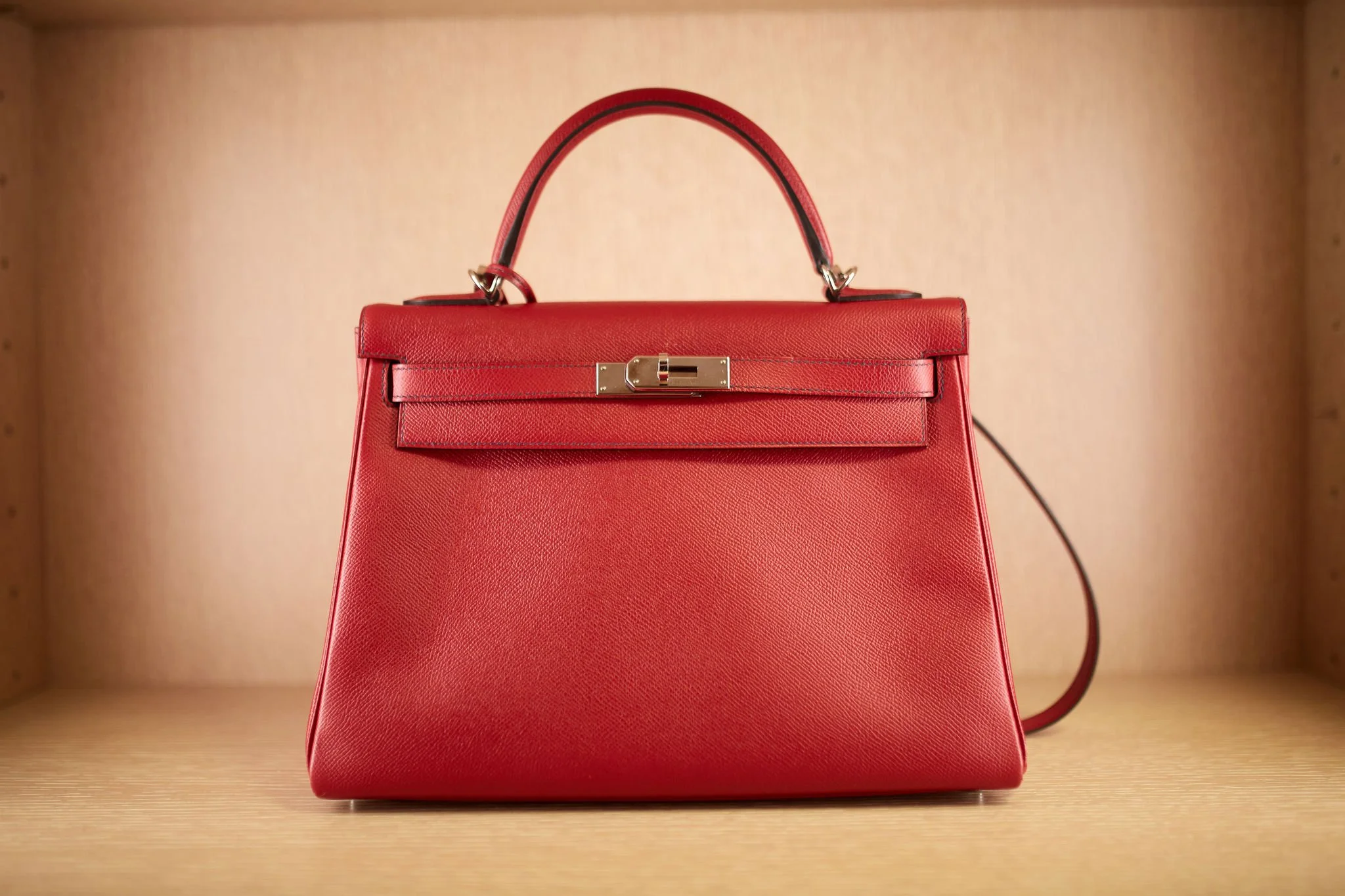 Red designer handbag with gold clasp on a wooden surface