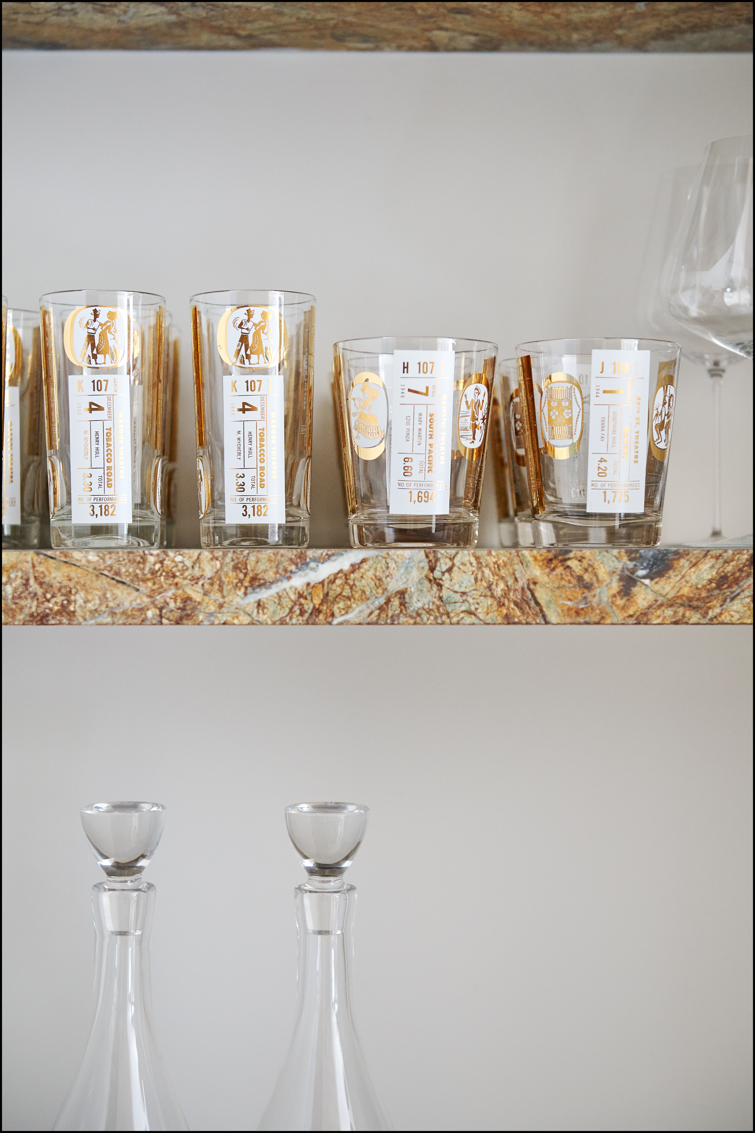Four empty champagne glasses with gold and white labels on a marble surface. The background of the image is white.