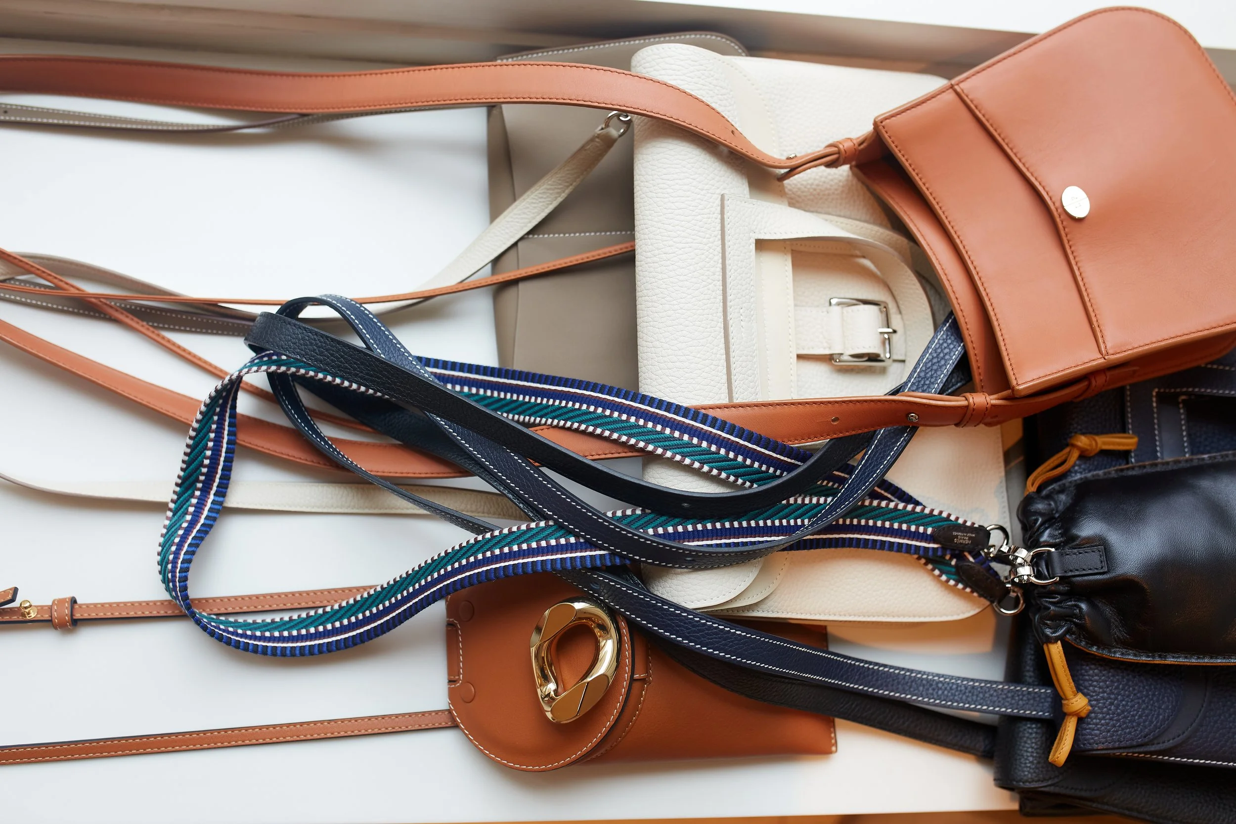 Various handbags and purses in different colors and styles laid out and ready to be donated to charity..