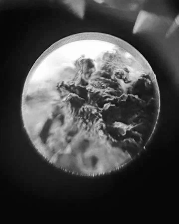 Black and white photo of a full moon with clouds surrounding it.