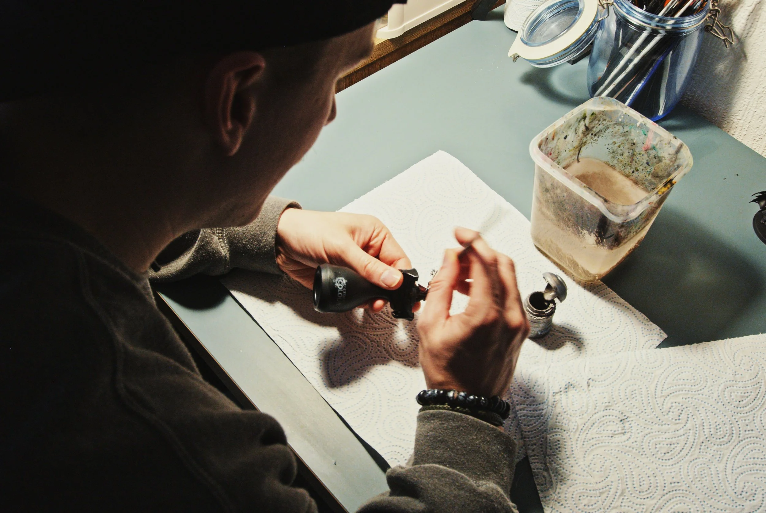 A hobbyist paints a wargaming miniature at home at a table