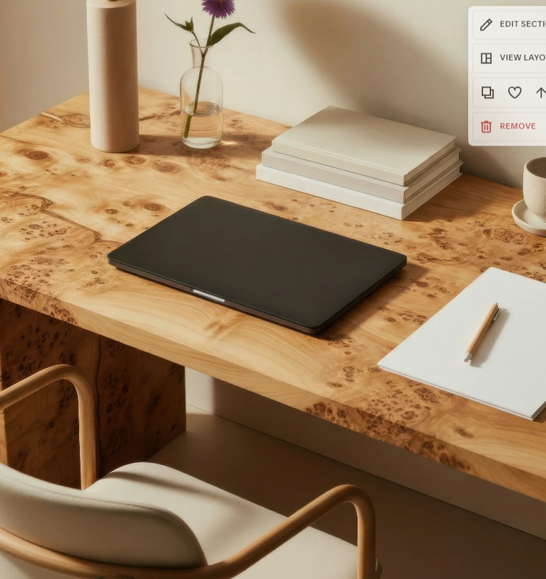 Wooden desk with closed black laptop, stack of white books, white notepad with a beige pen, white mug, glass vase with a purple flower, and a beige water bottle.