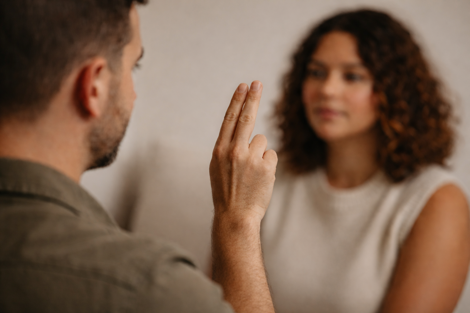 A man showing two fingers to a woman in a close-up, blurred background portrait.