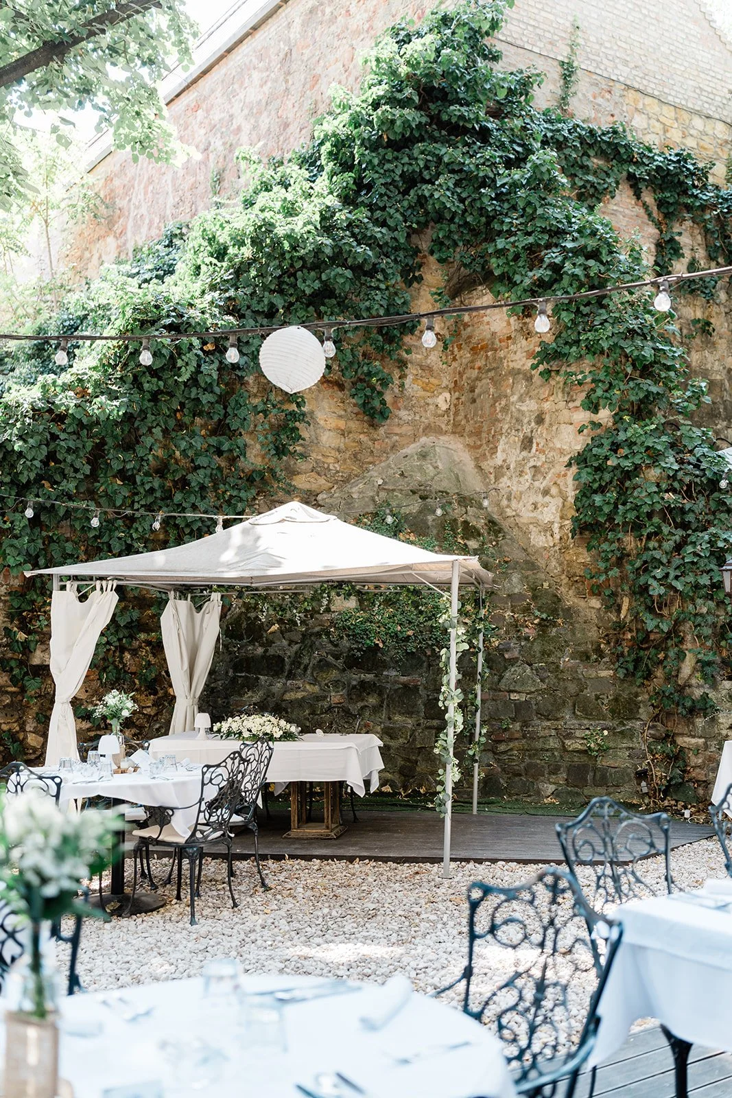 esküvői dekorral terített elegáns asztalok a kertben