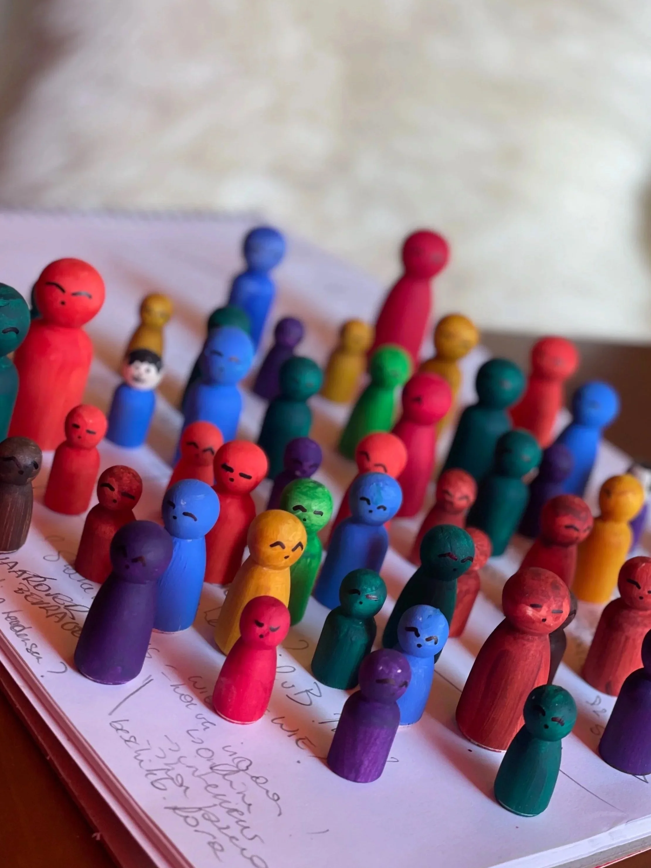Kleuren houten poppetjes op een papier met geschreven tekst.