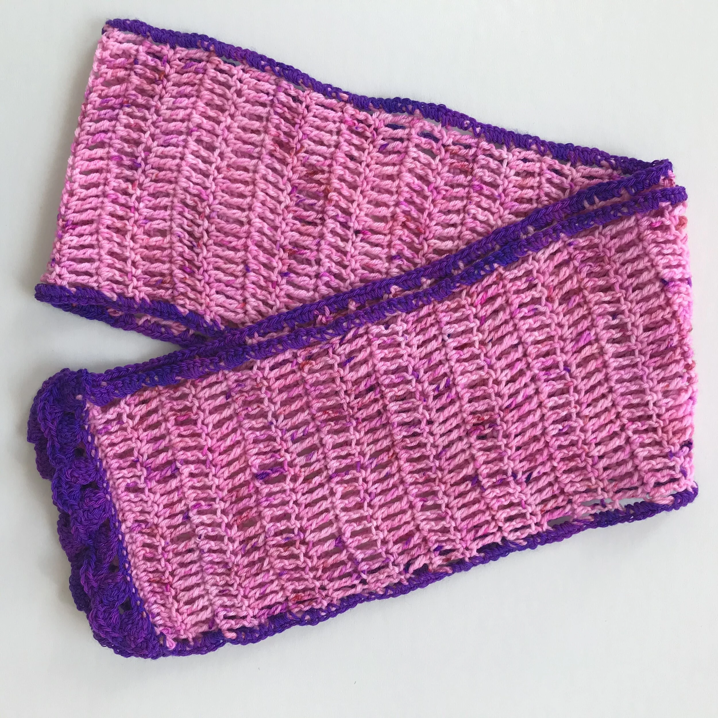 Handmade pink and purple crocheted dishcloths with a striped pattern and ruffled edges.