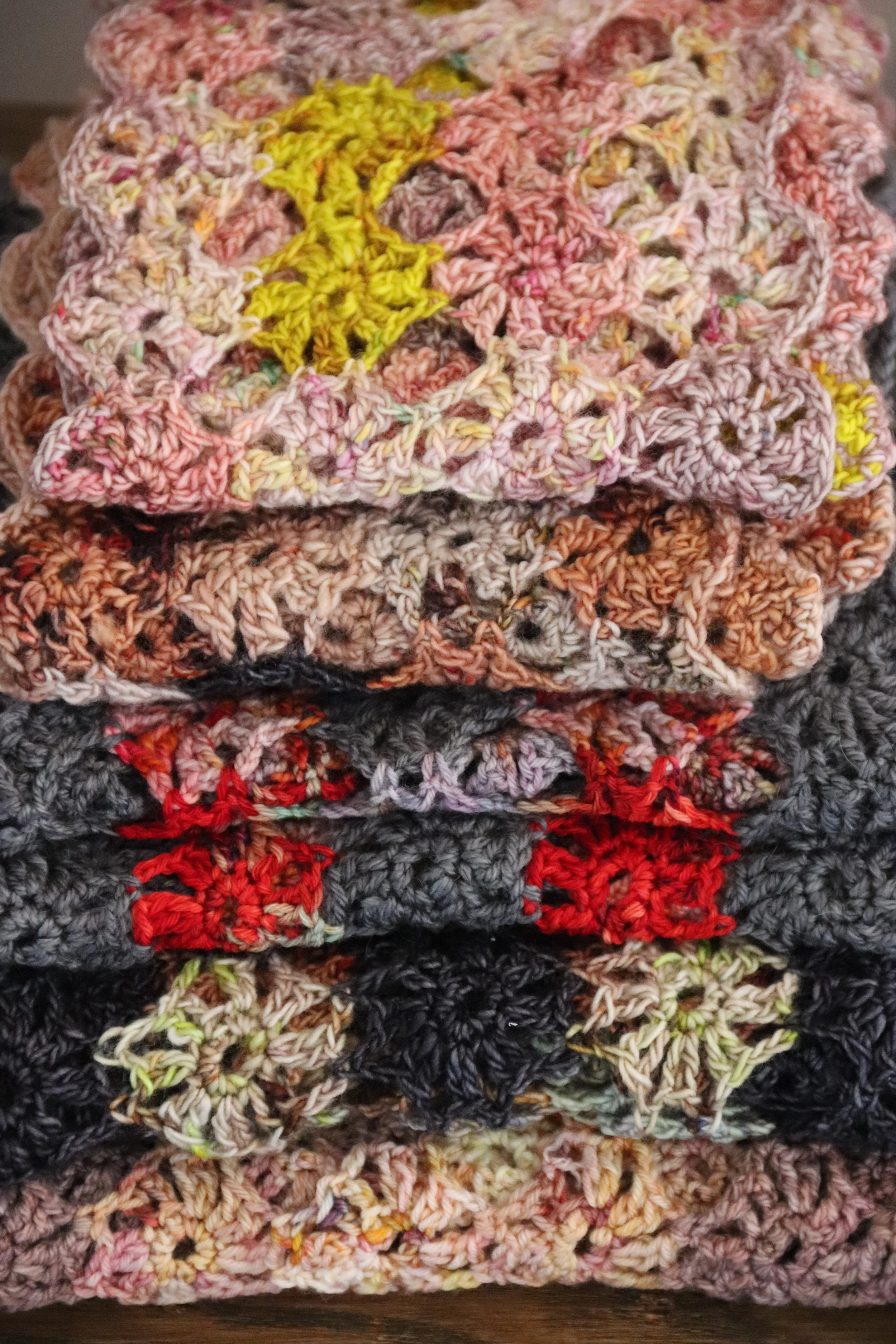 Stacked colorful hand-crocheted blankets with star patterns.