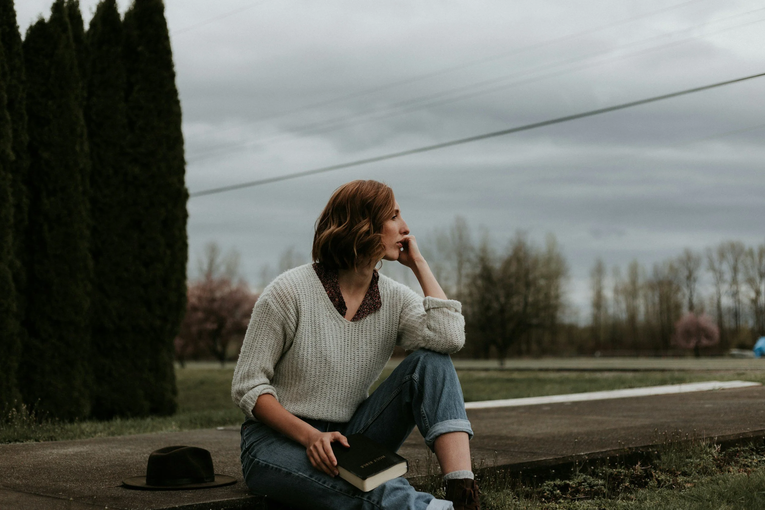 woman sitting outdoors with notebook on lap looking into the distance