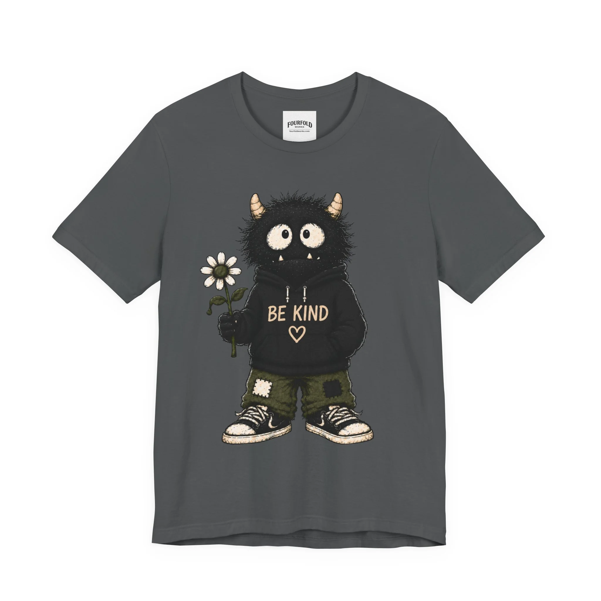 Front of the charcoal Be Kind T-shirt with a horned monster in a Be Kind hoodie and patched trousers.