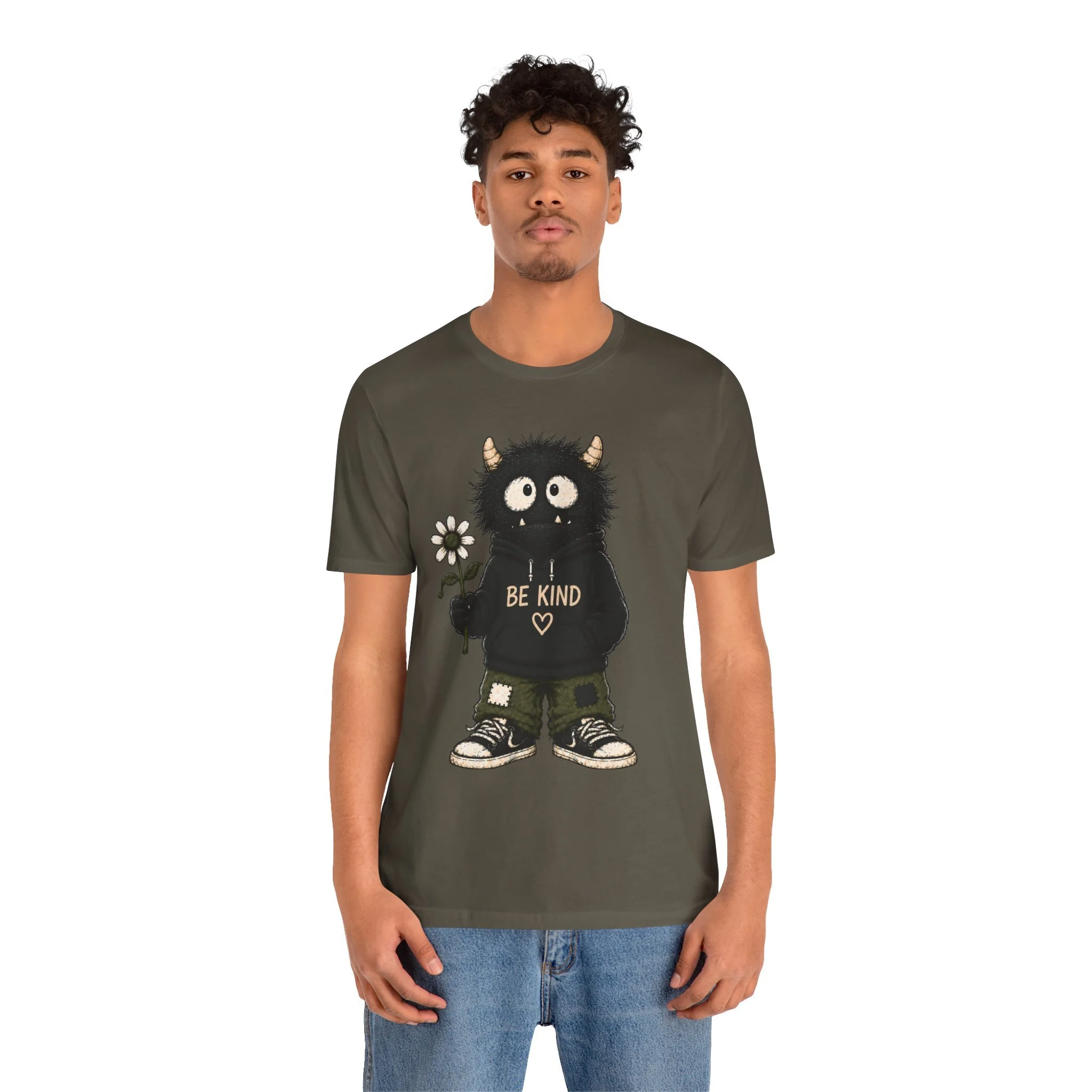 Second model wearing the olive-colored Be Kind monster graphic T-shirt, shown from the front.