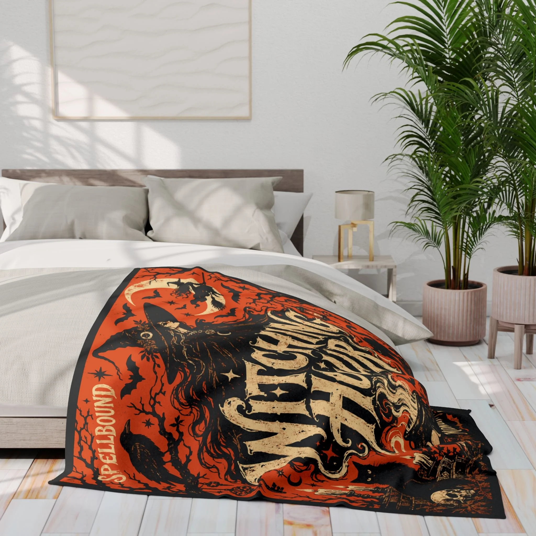 Witching Hour fleece blanket draped across a bed with orange and ivory vintage Halloween artwork.