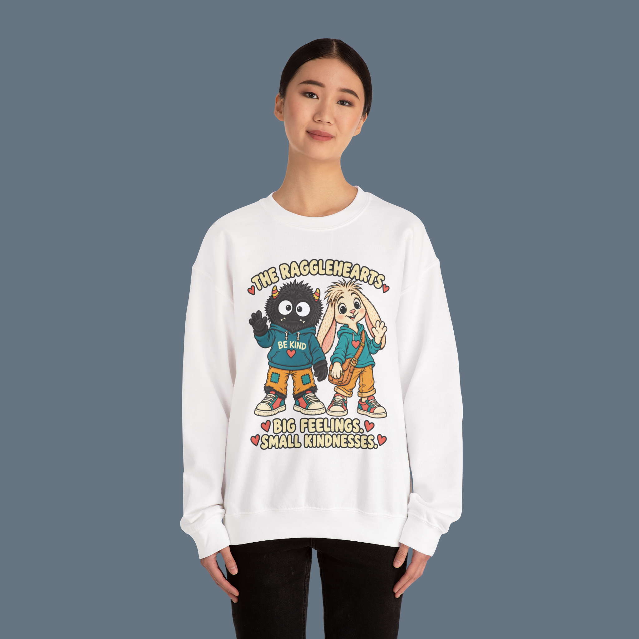 Ragglehearts White sweatshirt on a standing model against slate, with the complete enlarged BIG FEELINGS SMALL KINDNESSES design and approved Bimble and Loppin colors.