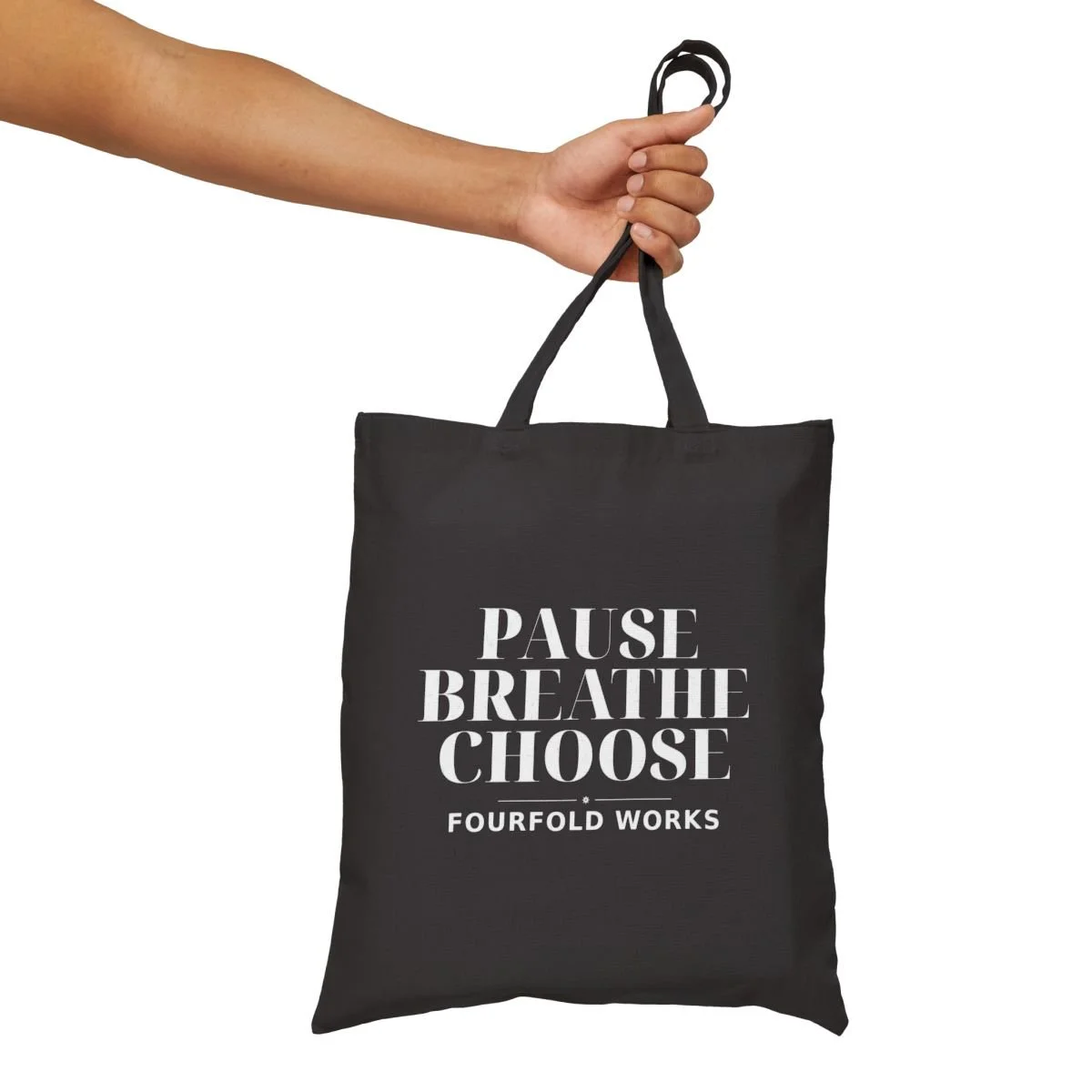 Black Pause Breathe Choose canvas tote held by its handles, showing the full white front lettering and Fourfold Works wordmark.