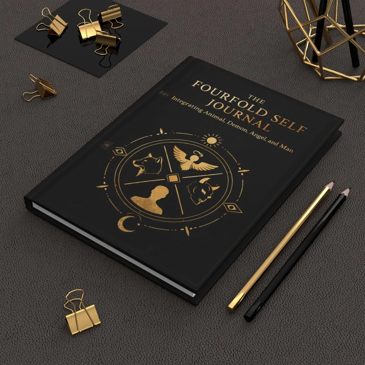 Fourfold Self black and gold compass lined journal on a charcoal desk with gold stationery.