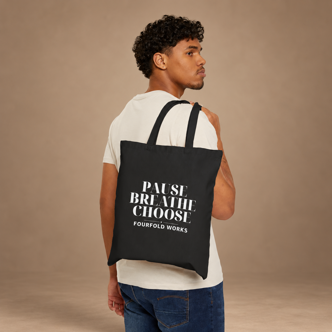 Model in a cream shirt and jeans carrying the Black Pause Breathe Choose tote in the approved warm taupe scene, with the original white lettering and print scale preserved.