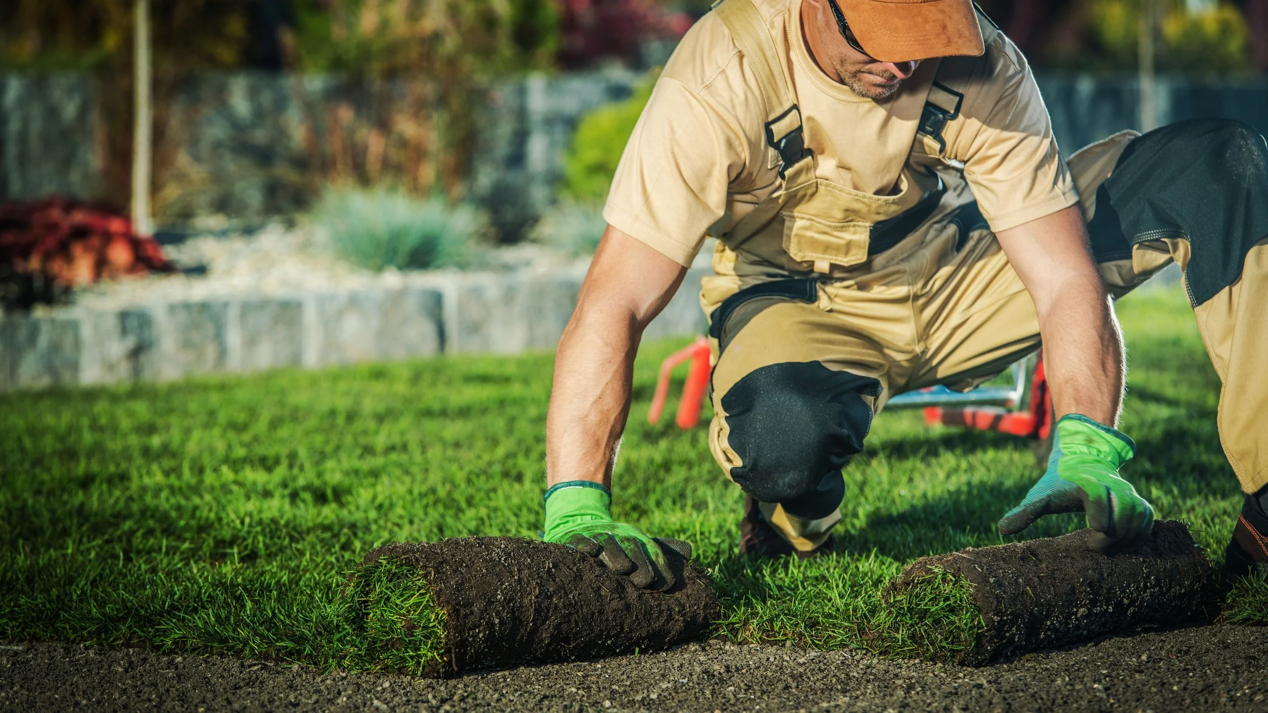 A man in work clothes and gloves planting grass.