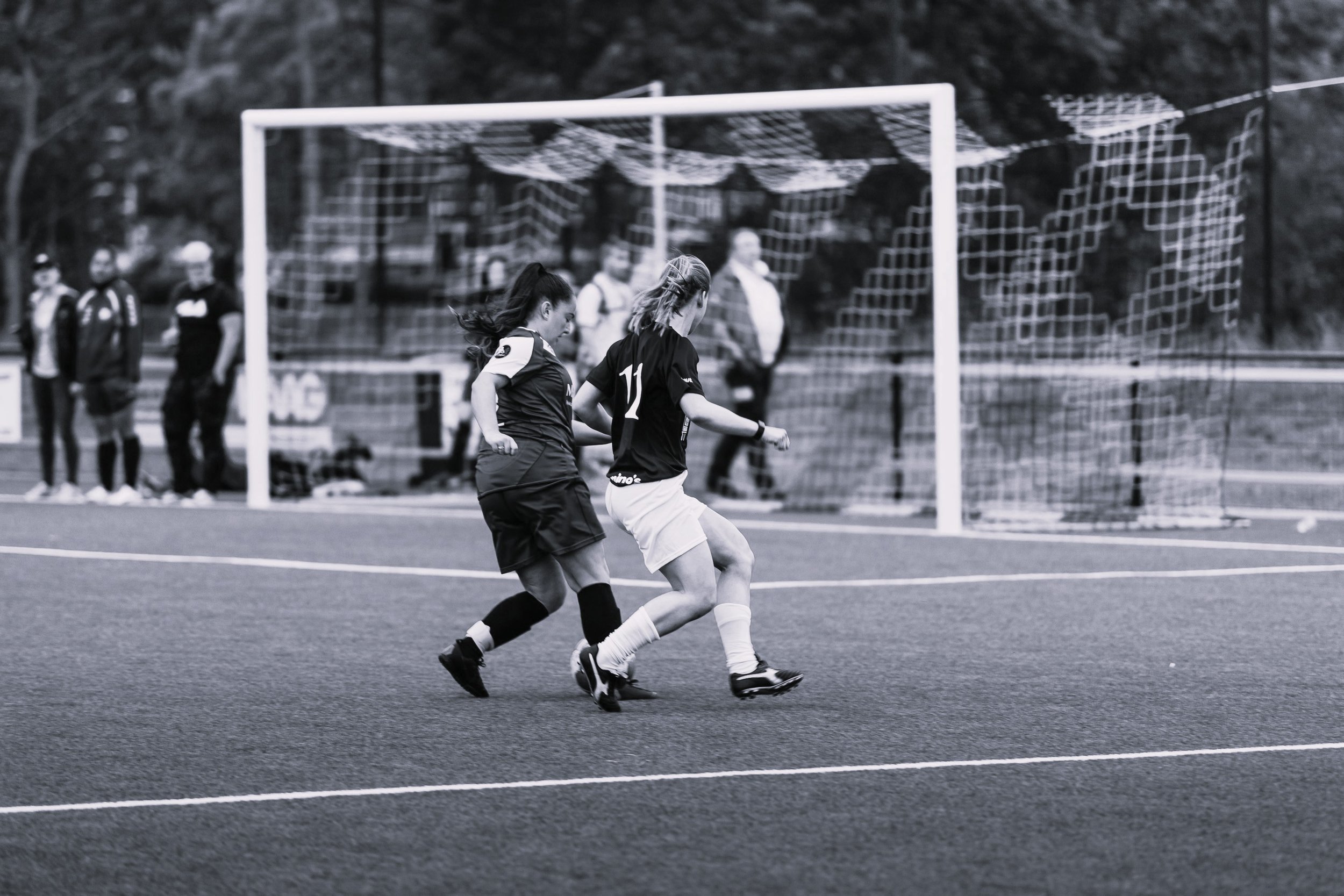 Two women playing football on astro pitch