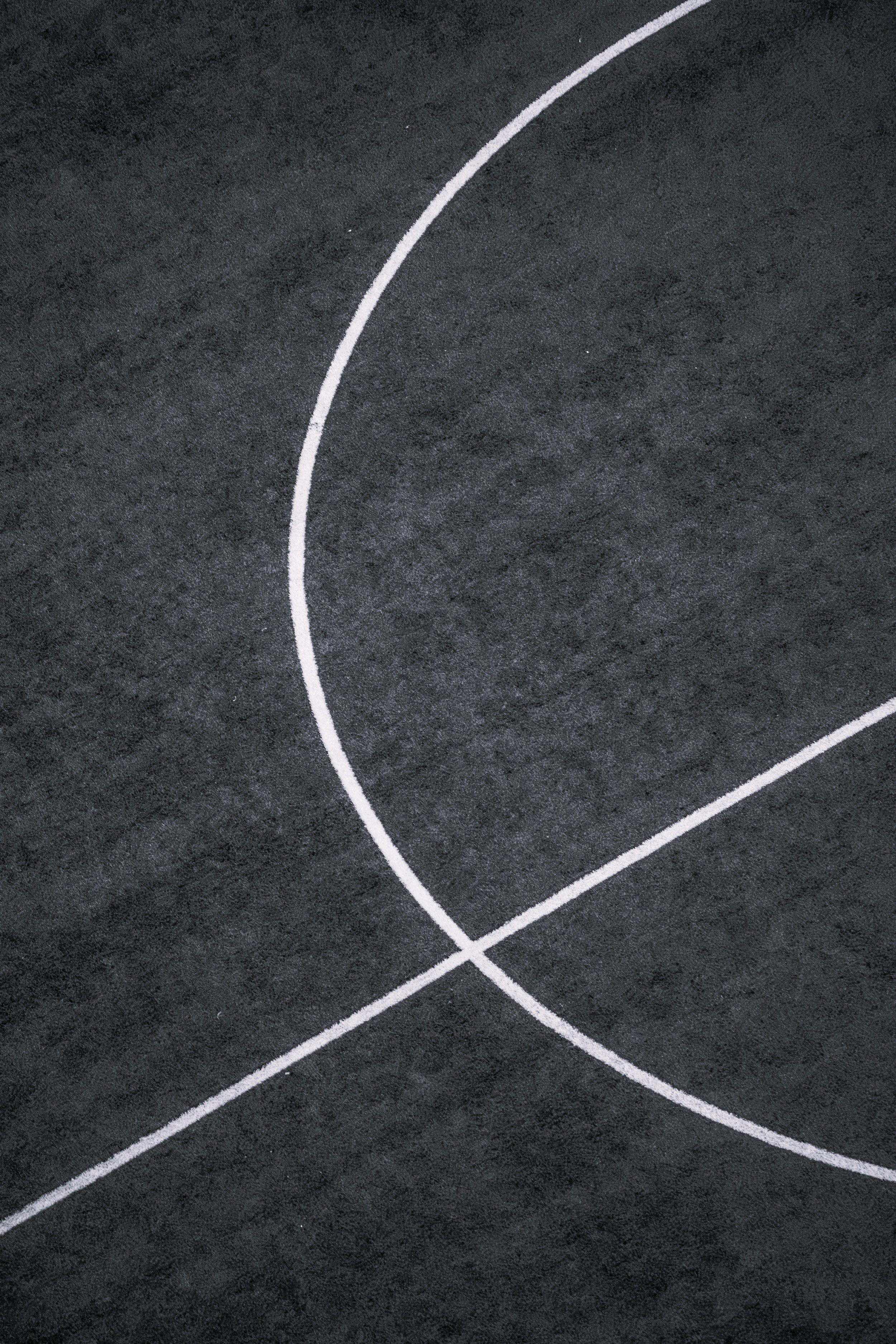 Close-up of a dark basketball court with white court lines.