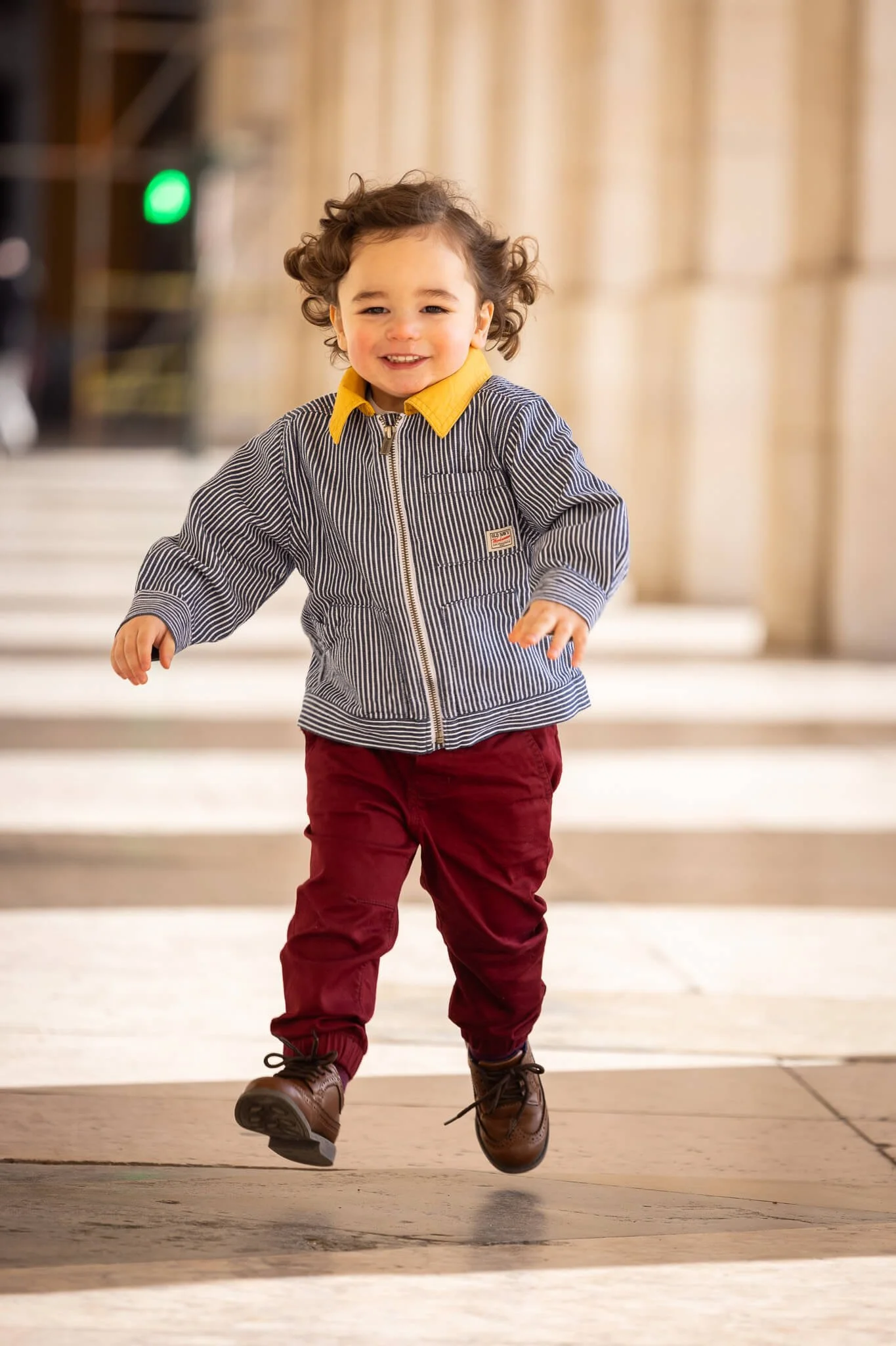 A young child running inside a building with columns and a marble floor.