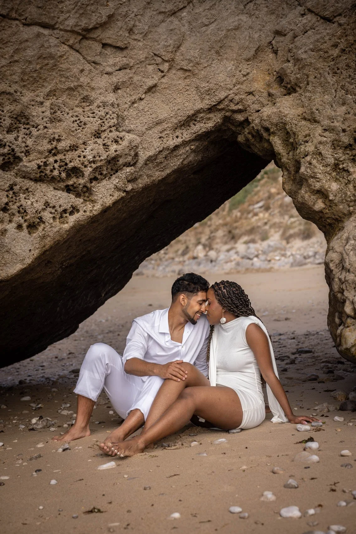 Secret Proposal photoshoot at secluded Sesimbra beach, Ribeira do Cavalo. Happy couple posing under the rock.