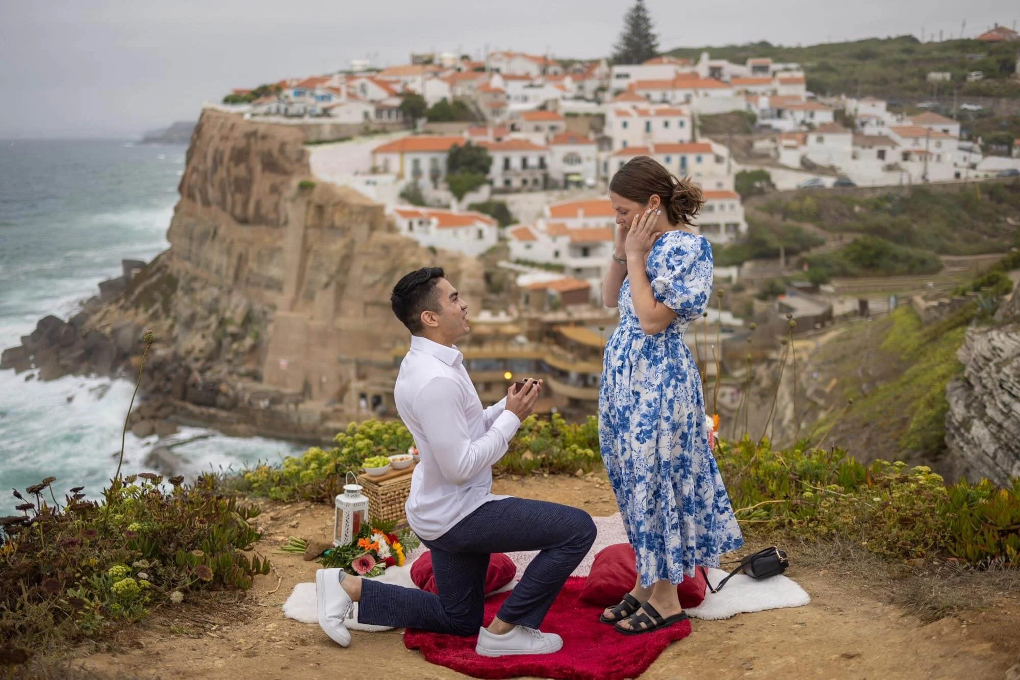 Secret Proposal Photoshoot at Azenhas de Mar, a surprised girl in blue tiled dress and a man in white shirt.