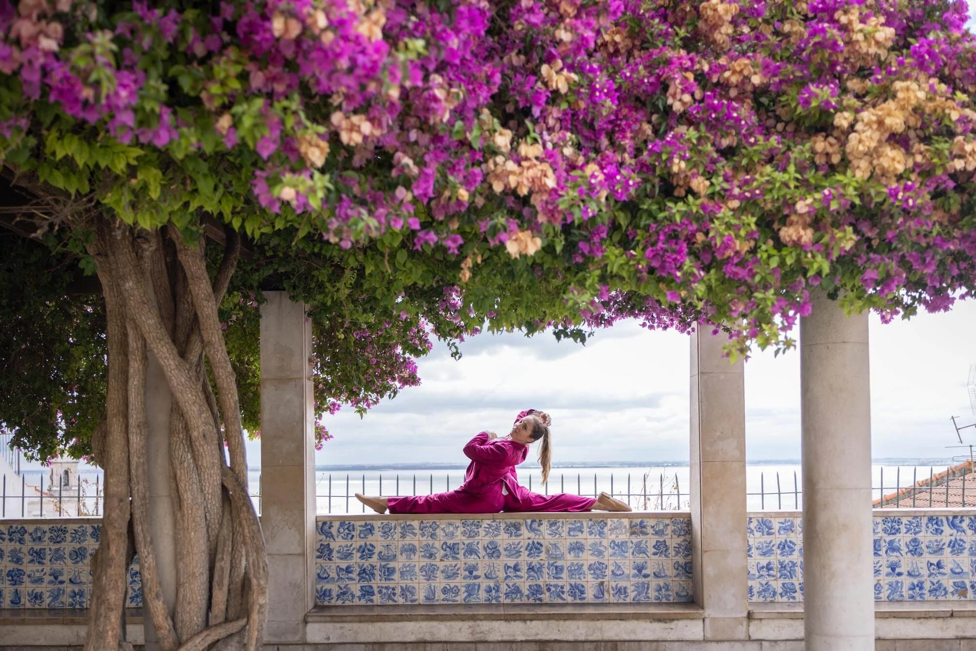 A girl is violet dress is doing a split during the photoshoot at Lisbon view point.