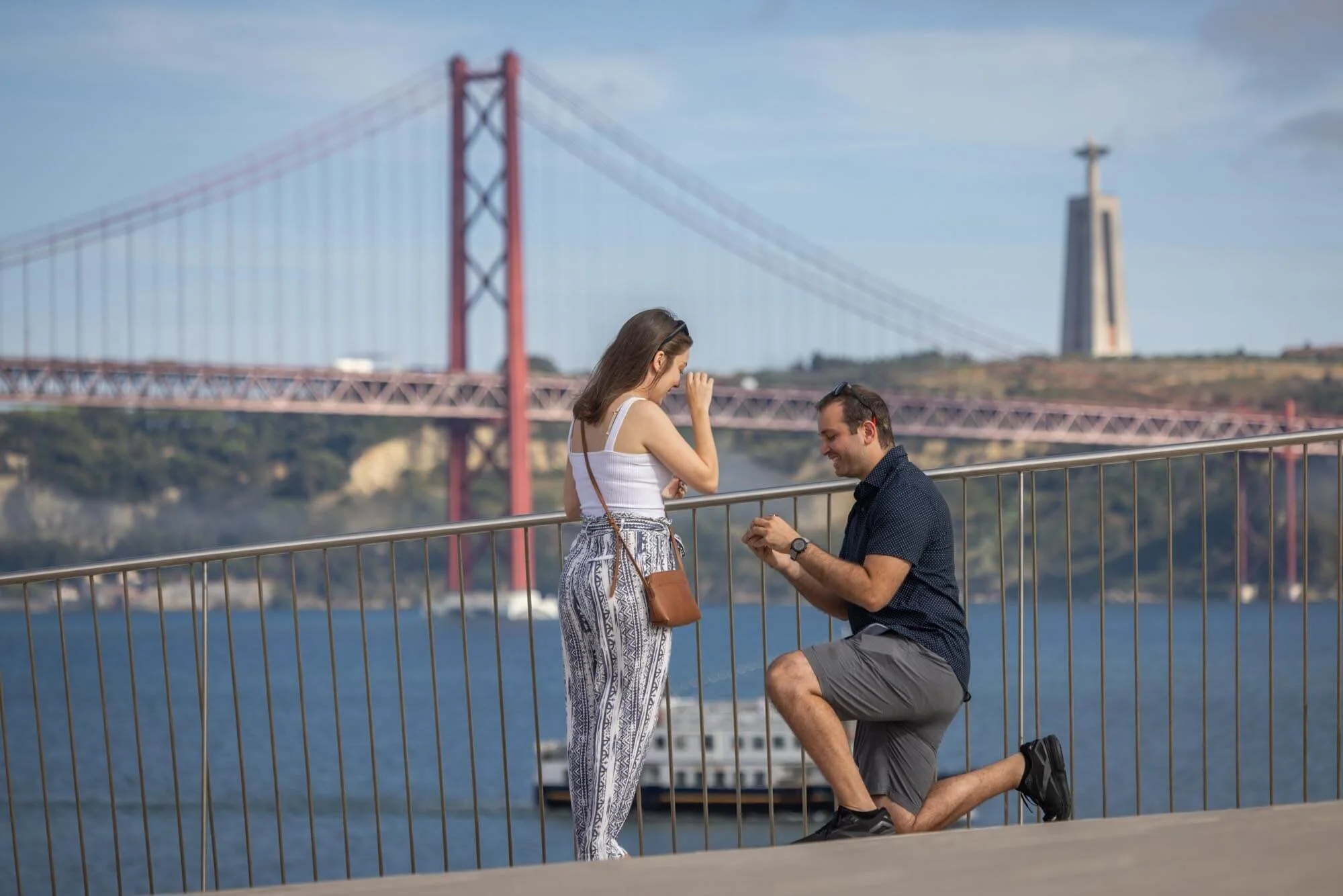 A man proposing to a woman on a waterfront with the Golden Gate Bridge in the background.