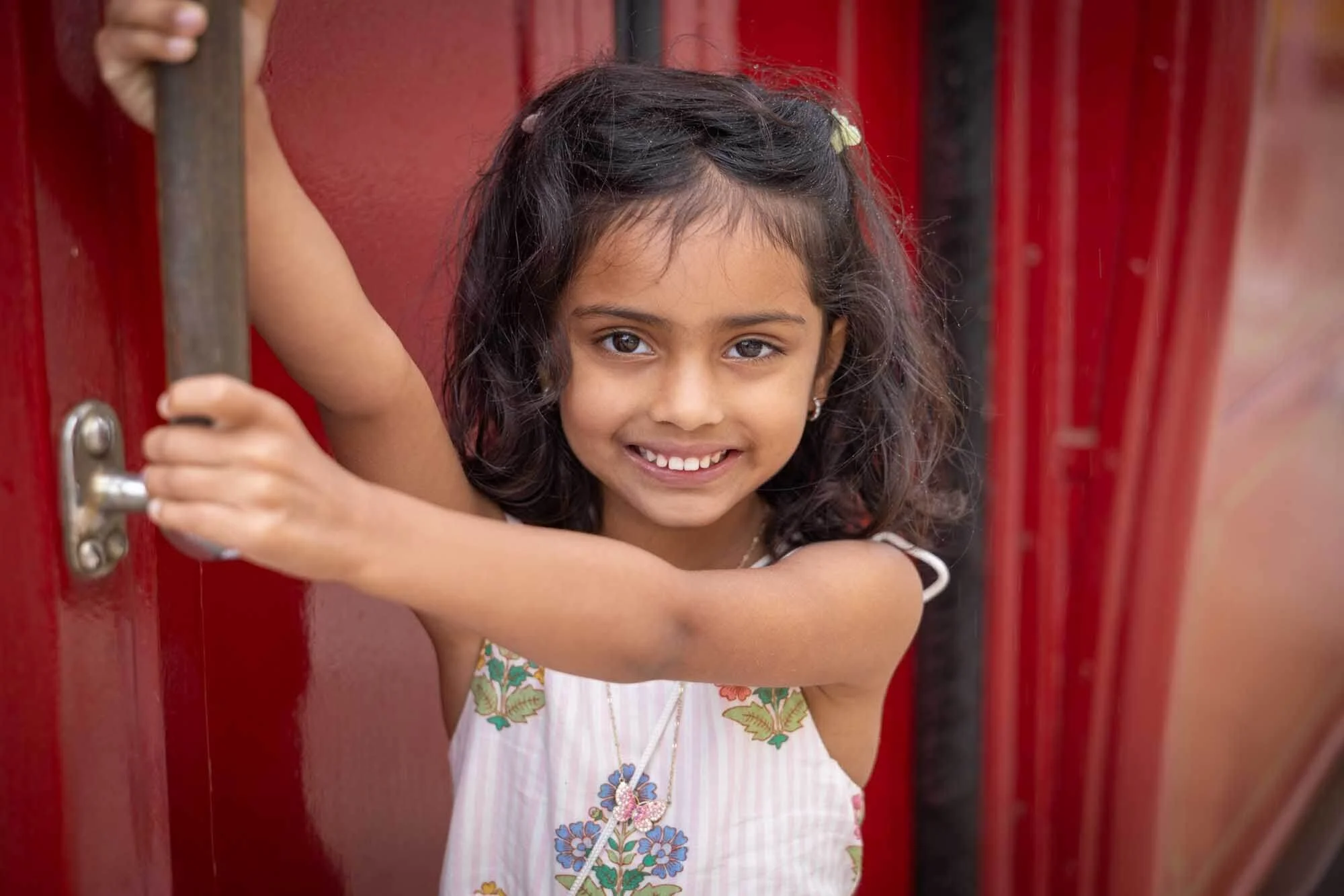 A young girl hanging from the Lisbon  tram while posing in front of a photographer. 