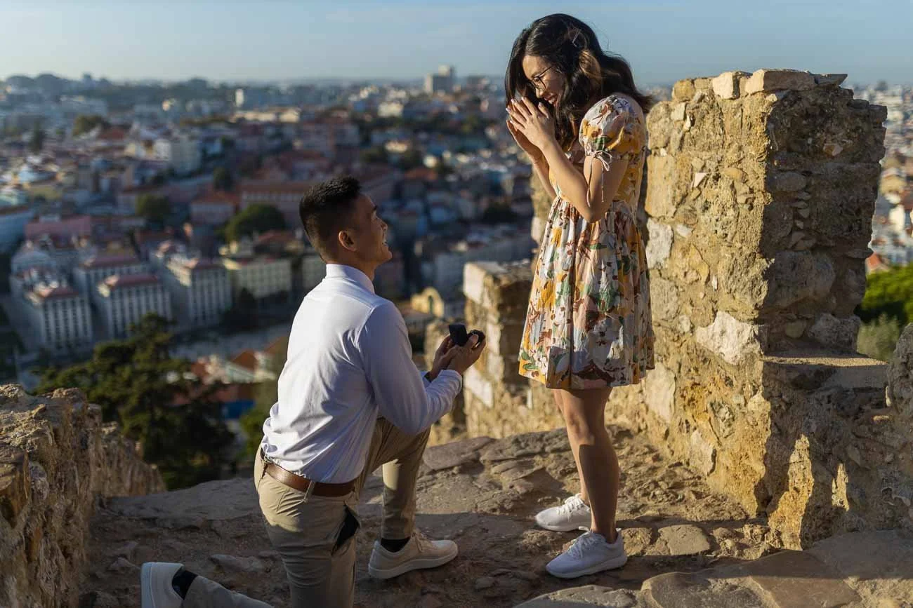 Guy proposing a girl on the stairs, during the Sunset Secret Proposal Photoshoot at São Jorge Castle with a lovely couple from USA.