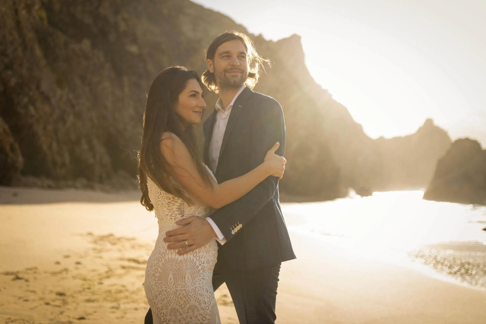 A couple embracing on a beach at sunset.