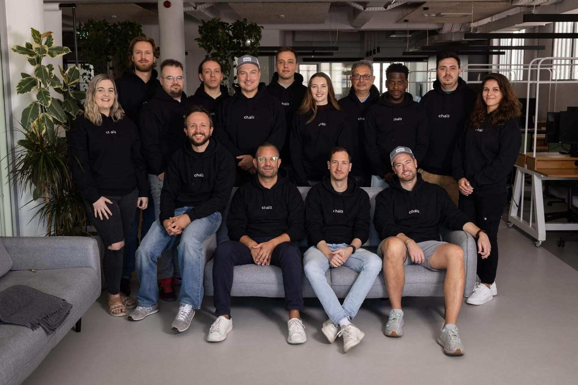 A group startup company photo at Lisbon cowering space. Everybody wears a black hoodie.