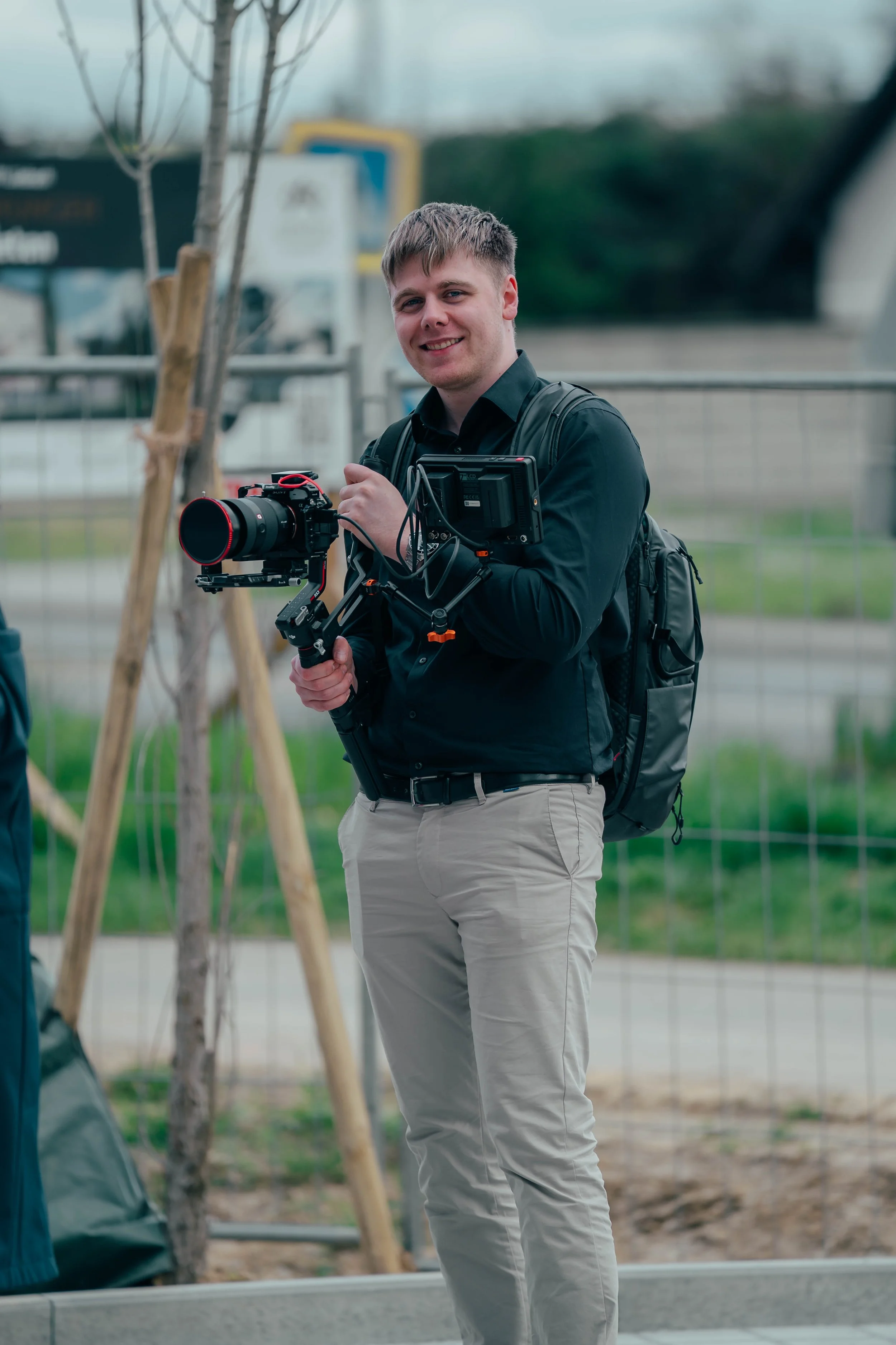 Junge Mann mit Kamera und Rucksack beim Filmen im Freien