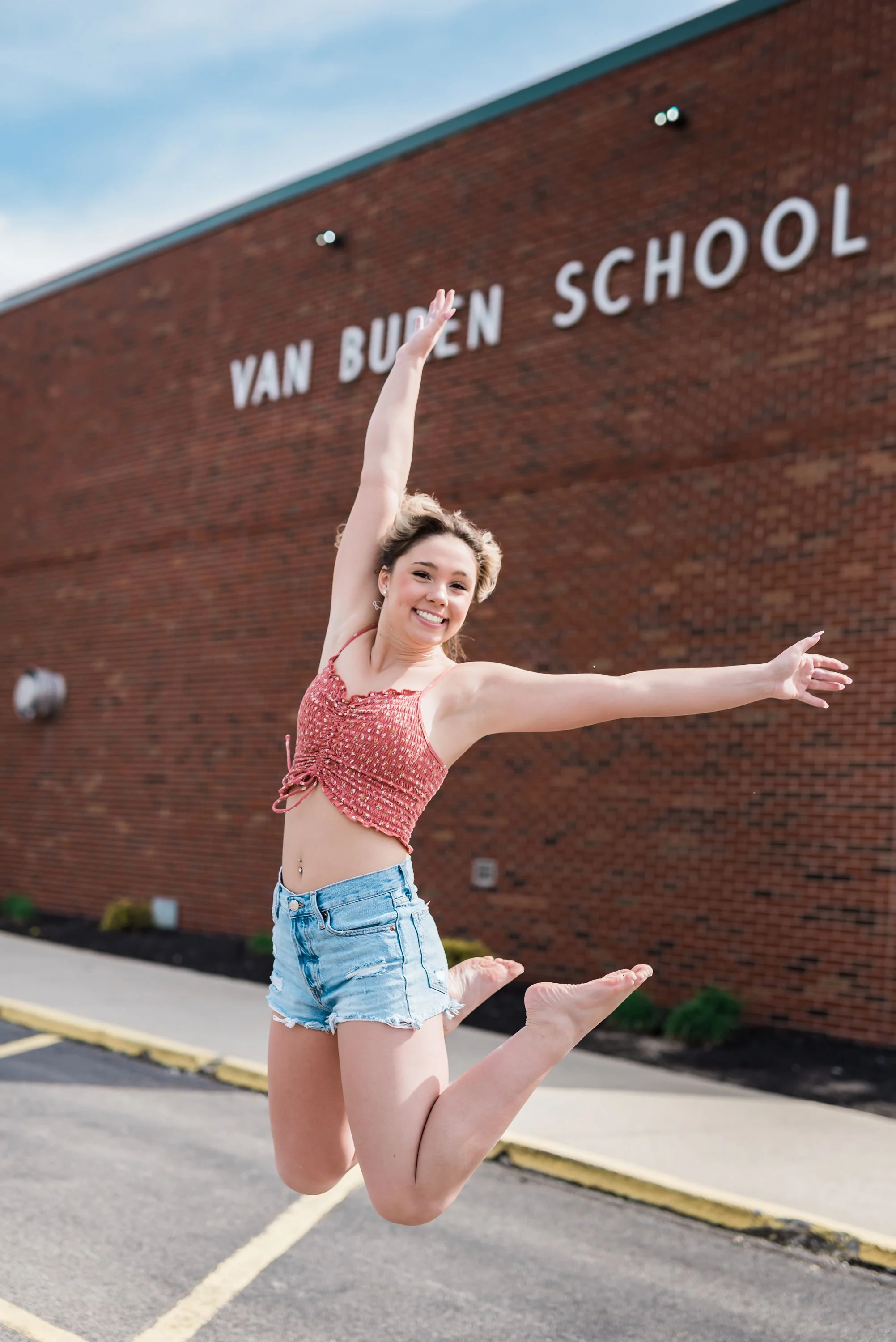 Young woman jumping happily in front of Van Buren School building.