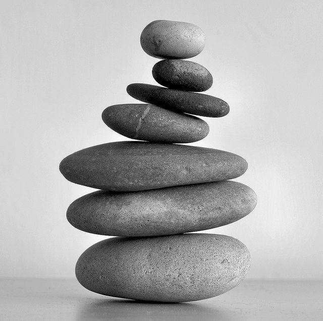Stack of smooth, rounded stones balanced on top of each other in decreasing size from bottom to top, black and white photograph