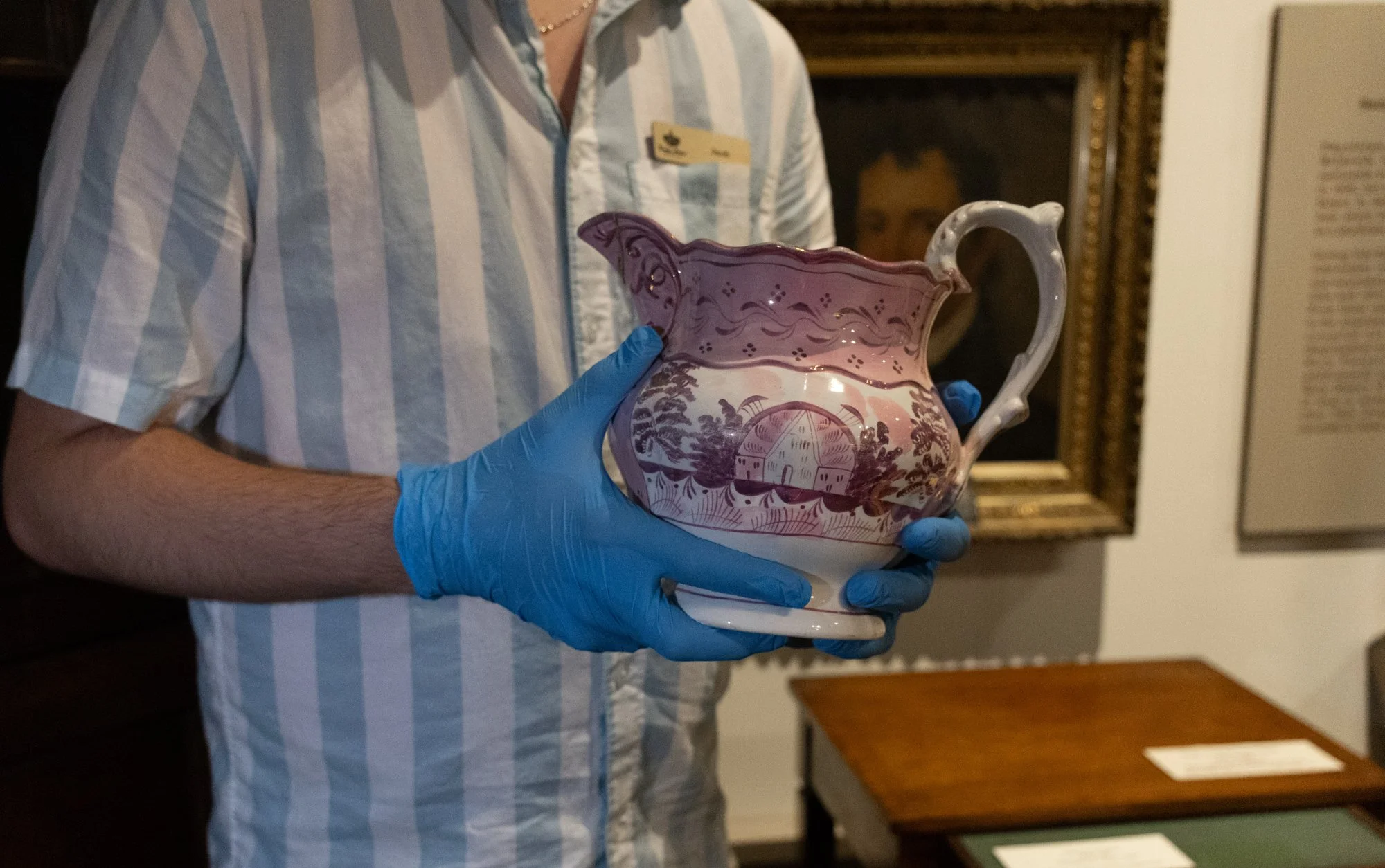 A person holds a pink and white pitcher while wearing protective blue gloves.