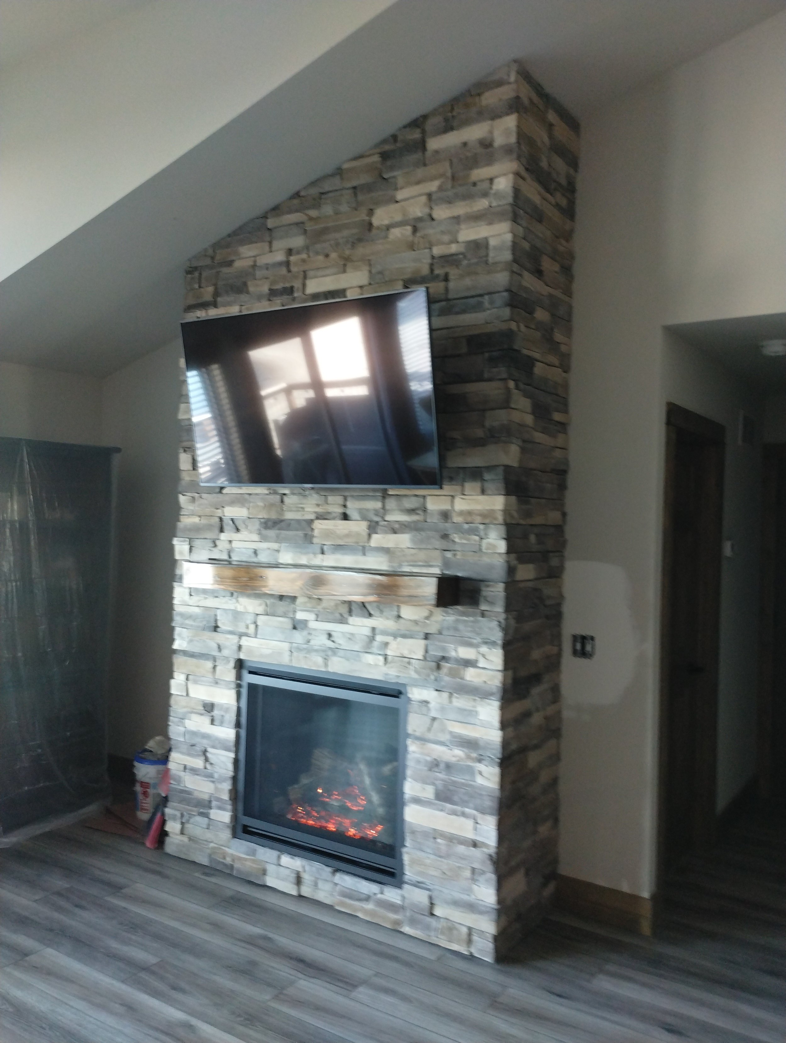 Living room with a stone fireplace and mounted flat-screen TV above it.