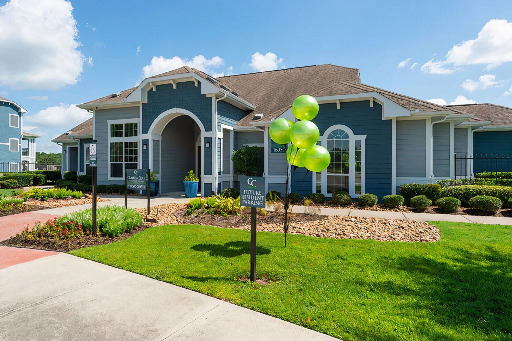 A modern building with white trim, surrounded by well-manicured gardens, and offering new resident parking.