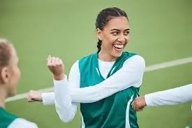 Two female soccer players on the field celebrating with a fist bump.