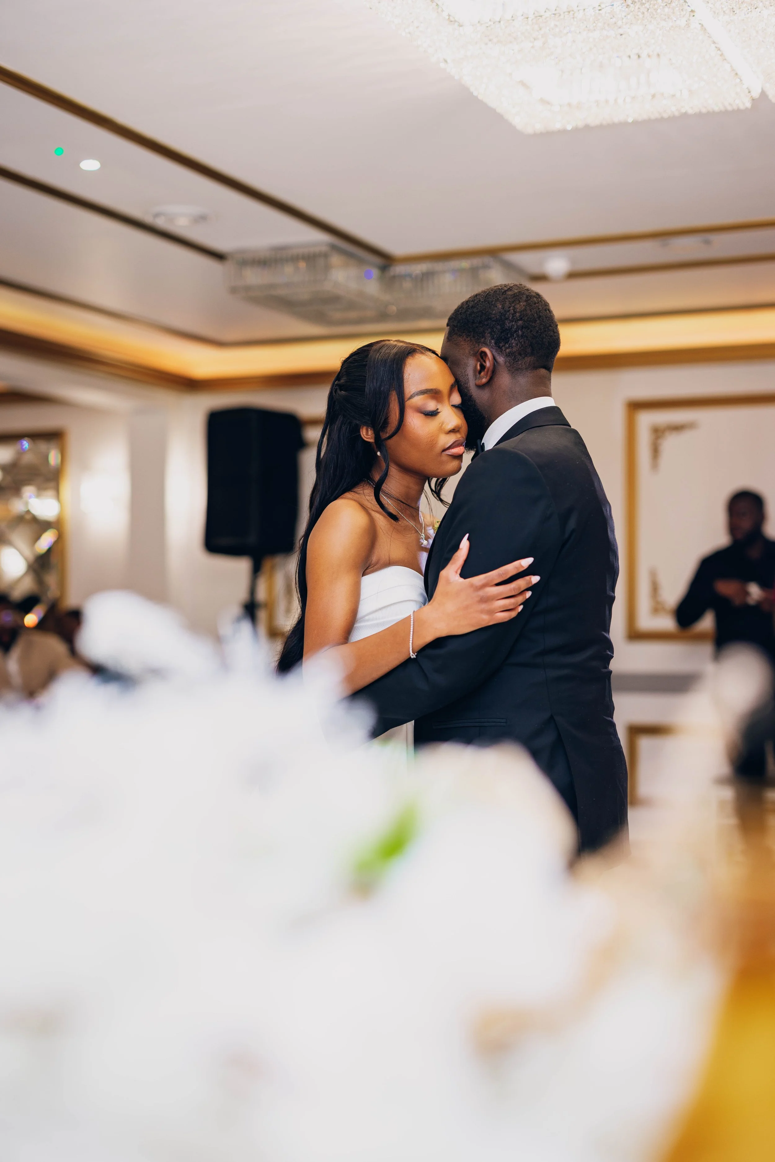 A bride and groom sharing a dance at their wedding reception, with elegant decor and guests in the background.