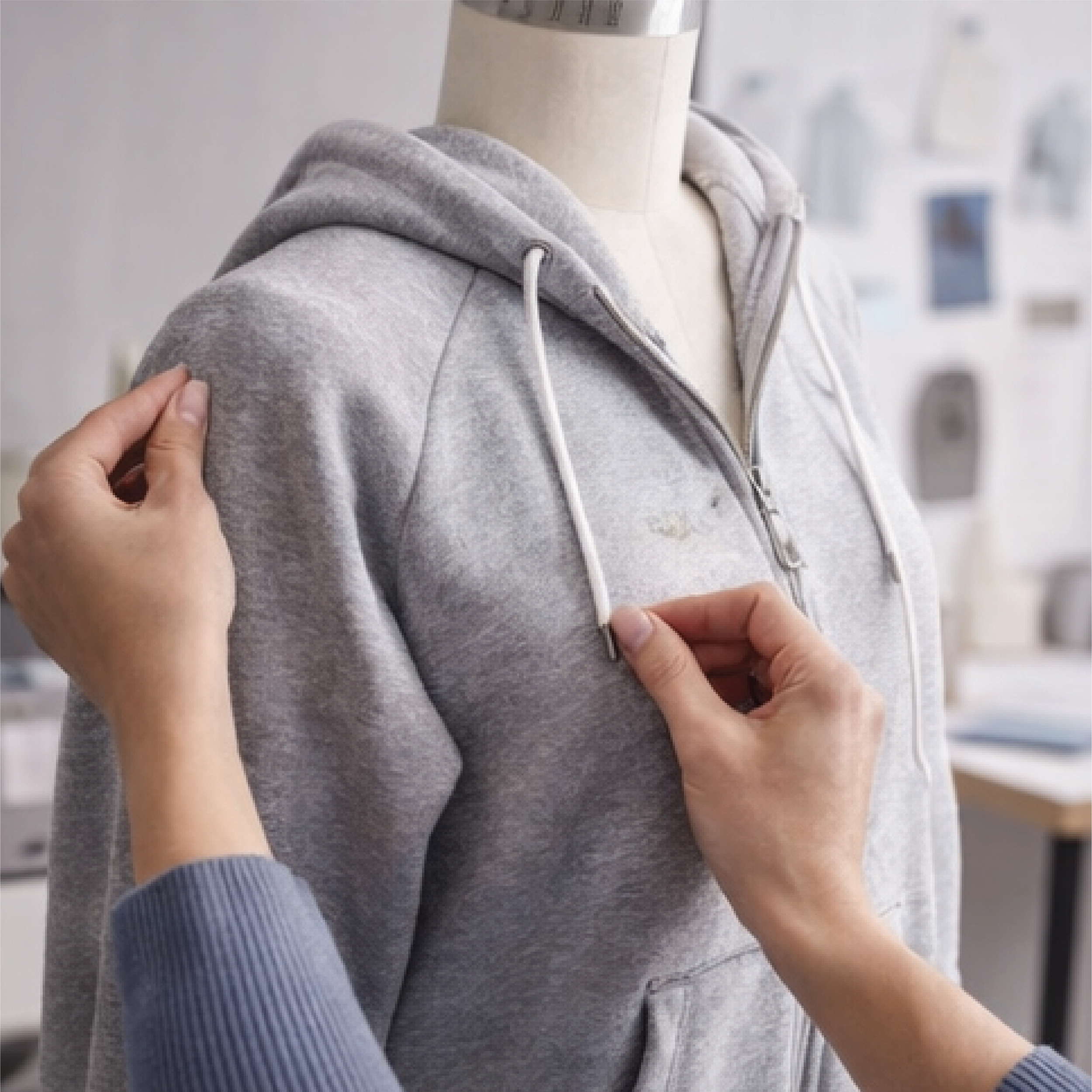 Person fitting a gray zip-up hoodie on a mannequin or person for size or style check.