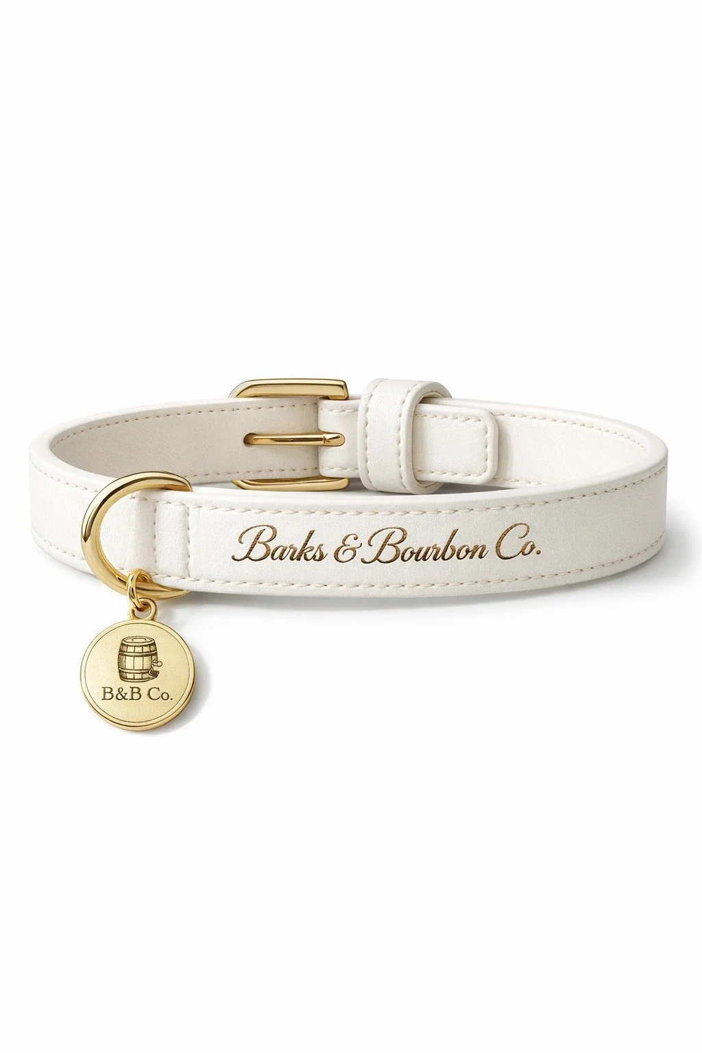 A white leather pet collar with gold accents, engraved with "Barks & Bourbon Co." and a gold tag featuring a barrel illustration and the text "B&B Co."