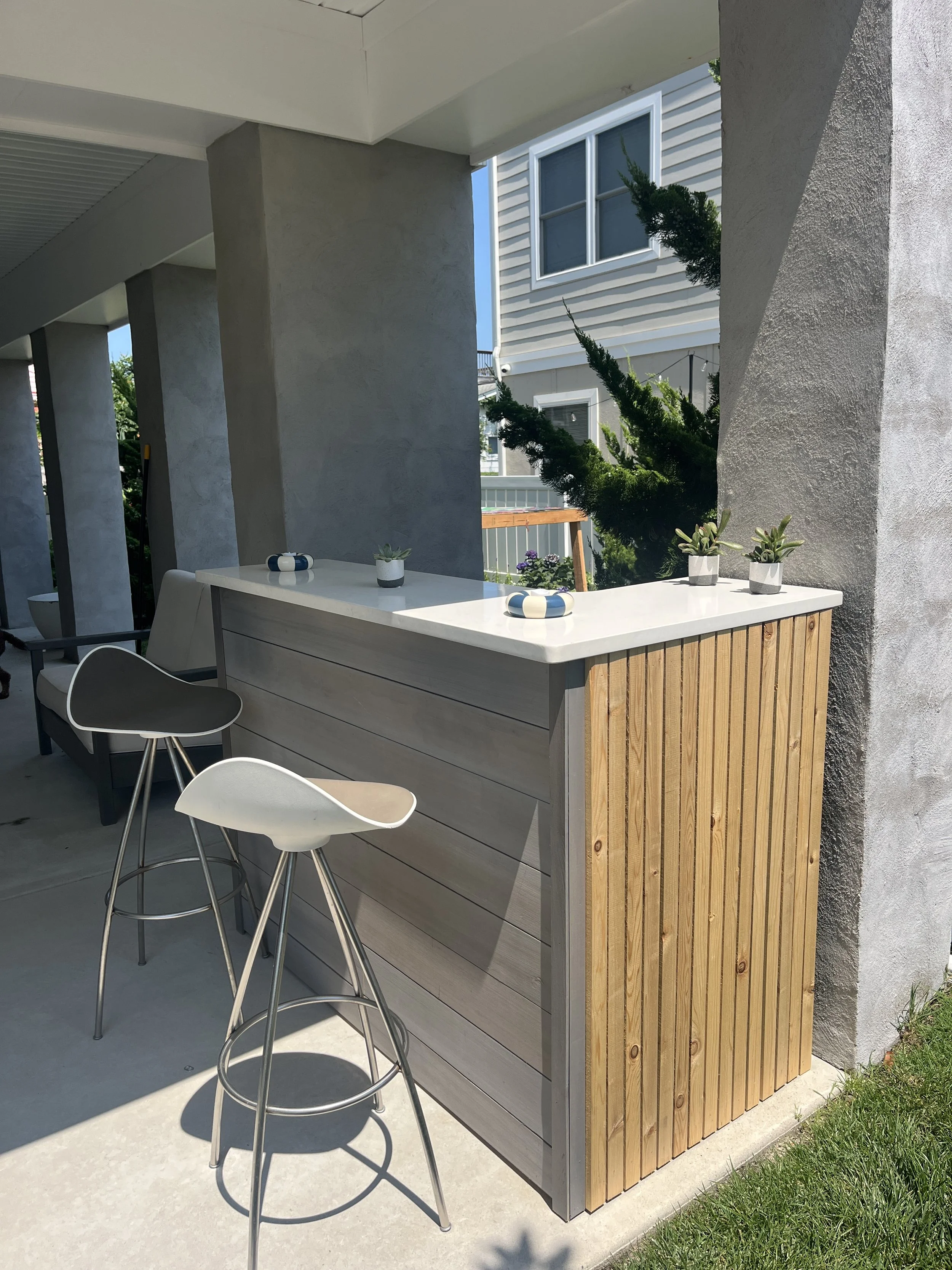 Small outdoor bar with repurposed Alaskan Yellow Cedar siding with unique "Williwaw" finish.  Along with a repurposed quartz kitchen countertop and small cedar strips.
