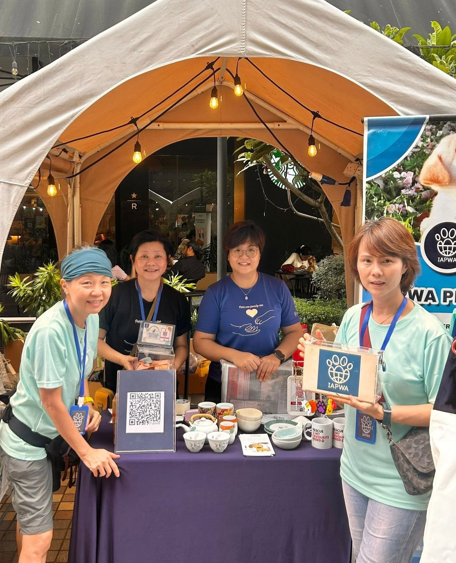 Four women standing in front of a table fundraising for IAPWA