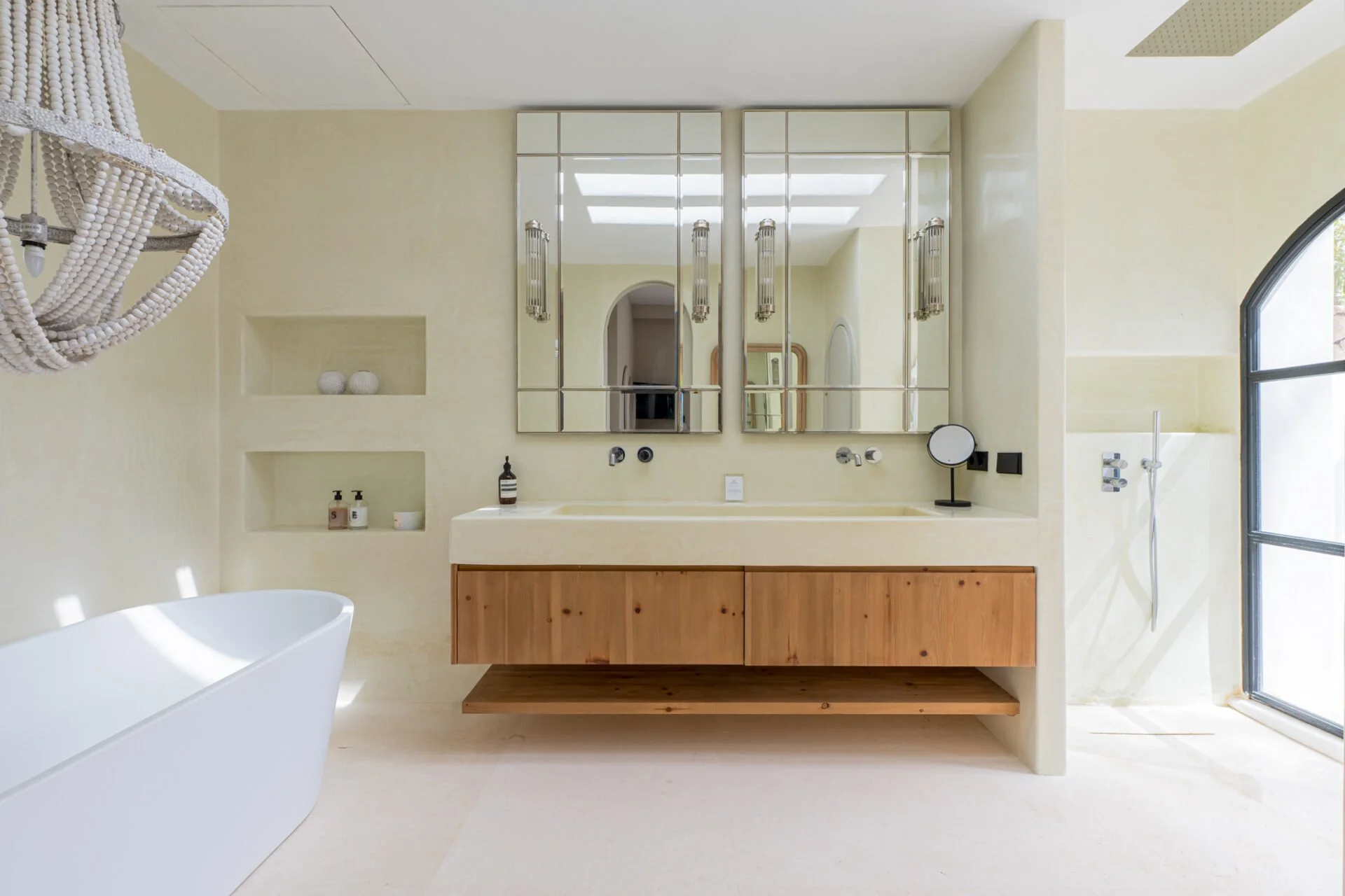 Modern ibiza bathroom with a minimalist design, featuring a large mirror, a white sink, a wooden cabinet, a white bathtub, and a walk-in shower with a glass door.