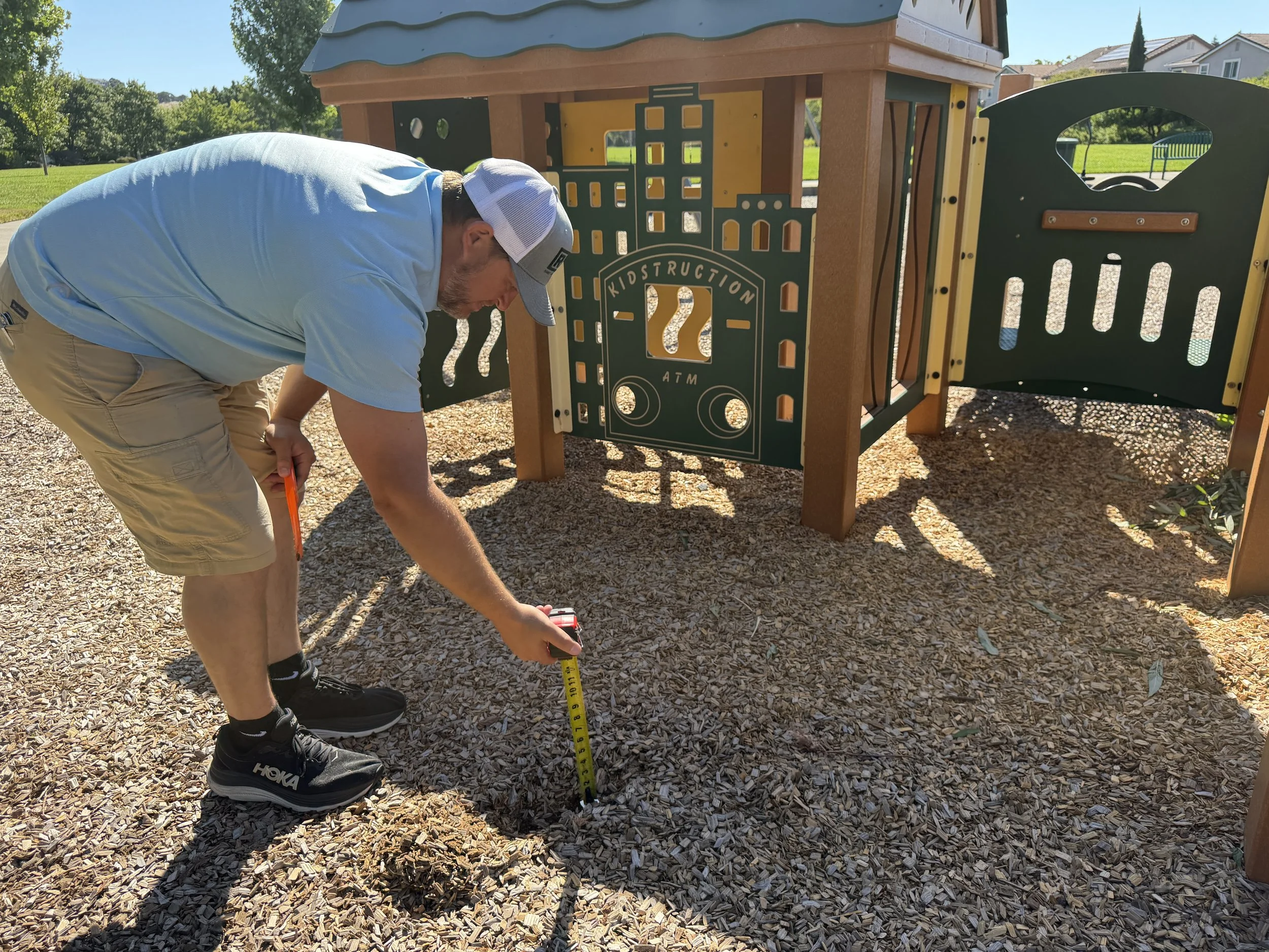 Playground Inspector measuring fill height on playground surface