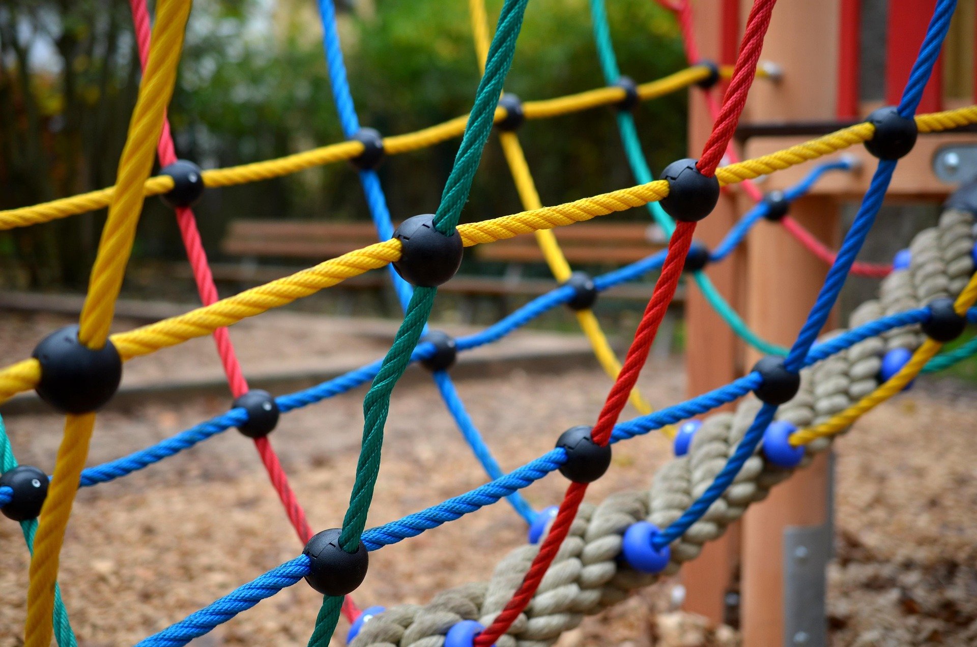 Close-up view of colorful ropes on a playground climbing structure with a natural outdoor background.