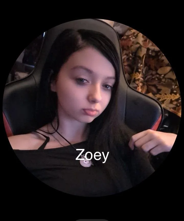 A young woman with dark hair sitting in a gaming chair, looking at the camera with a neutral expression, wearing a black top and a necklace, with autumn leaves in the background. The caption reads "Zoey."