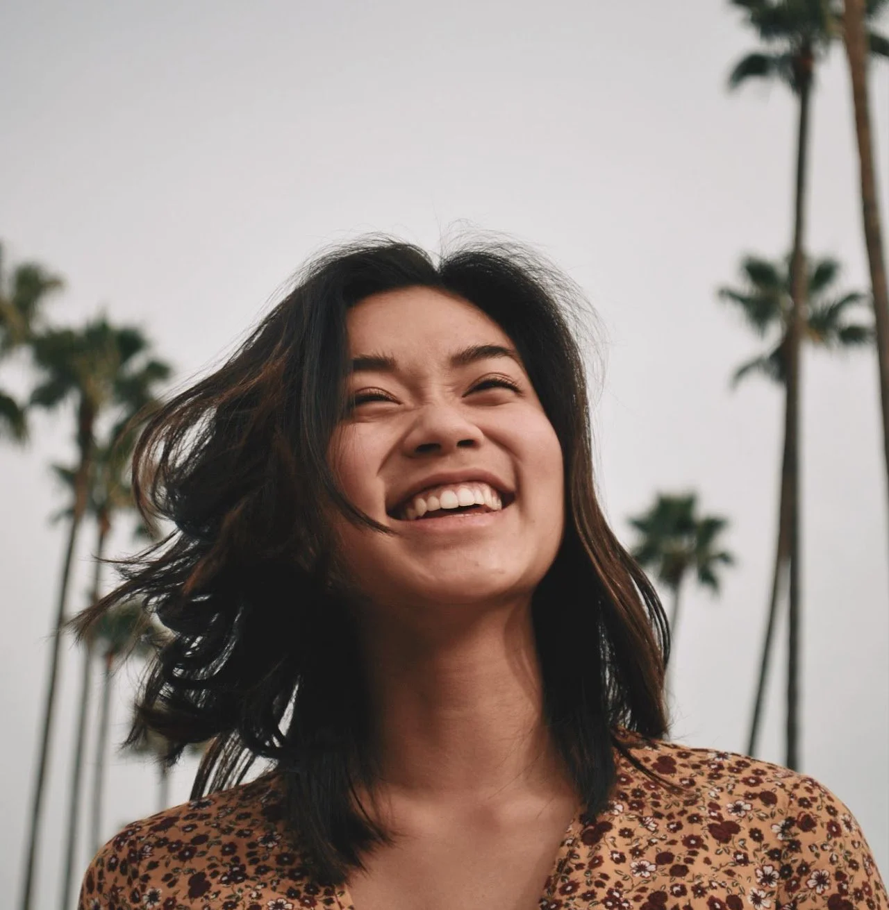 woman smiling in front of palm trees