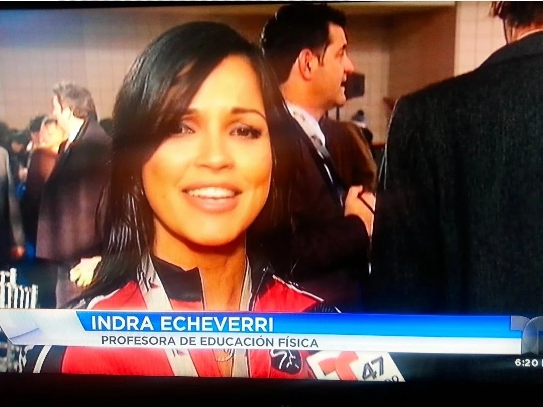 A woman, identified as Indra Echeverri, speaking into a microphone during a television interview at a formal event or gathering.